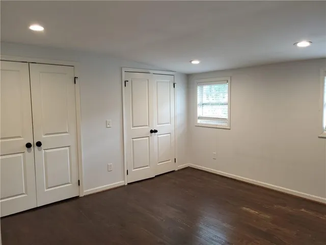 a view of an empty room with wooden floor and closet area