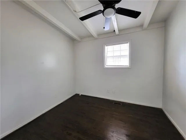 an empty room with wooden floor ceiling fan and windows