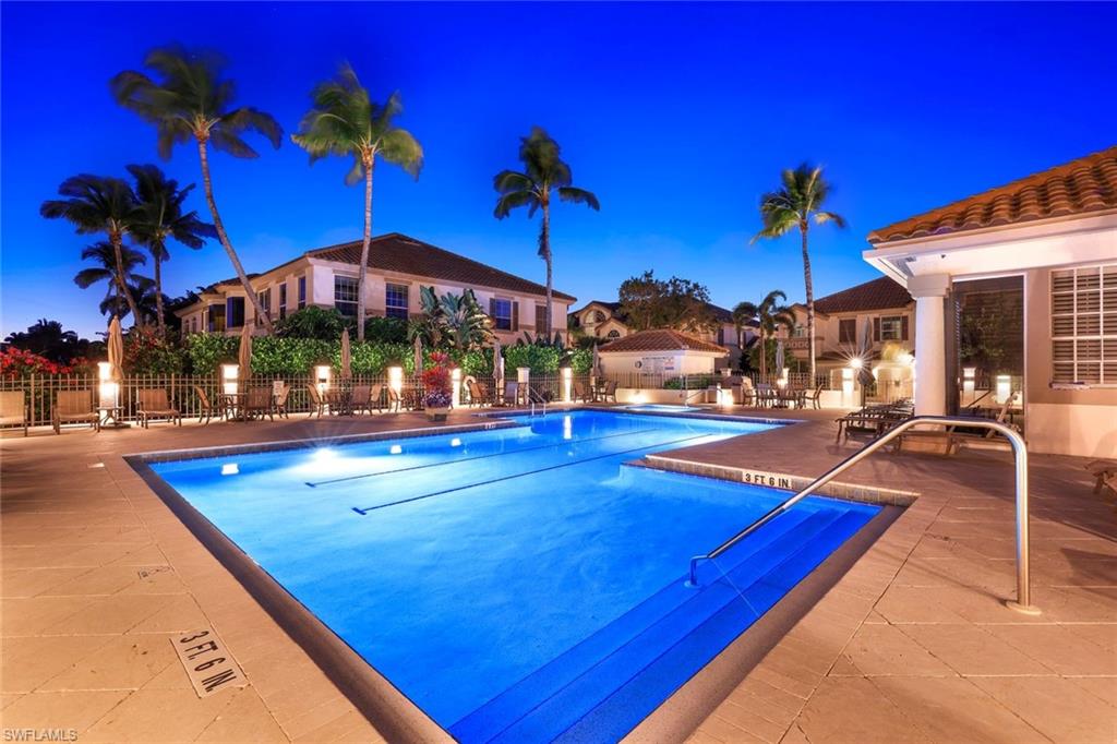 269 Colonade Circle, Unit 2802 Naples, FL 34103 - Photo 1 of 50 a view of a pool with a table and chairs under an umbrella