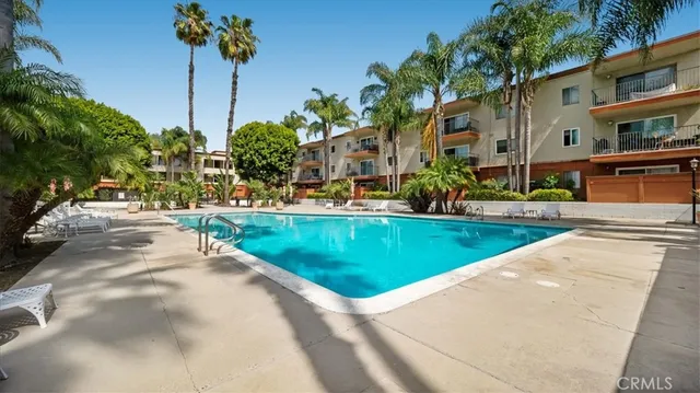 a view of a swimming pool with a yard and palm trees