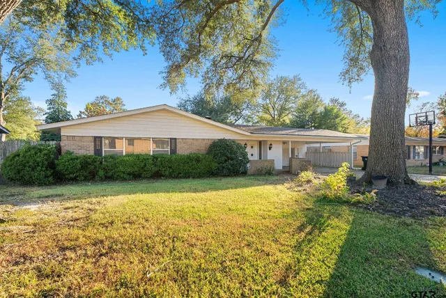 a front view of house with yard and trees in the background