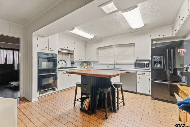 a kitchen with a table chairs wooden floors and a view of living room