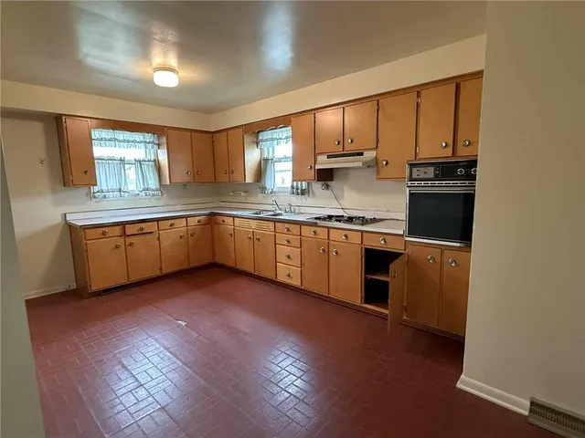 a kitchen with stainless steel appliances granite countertop wooden cabinets a sink a stove a dining table and chairs