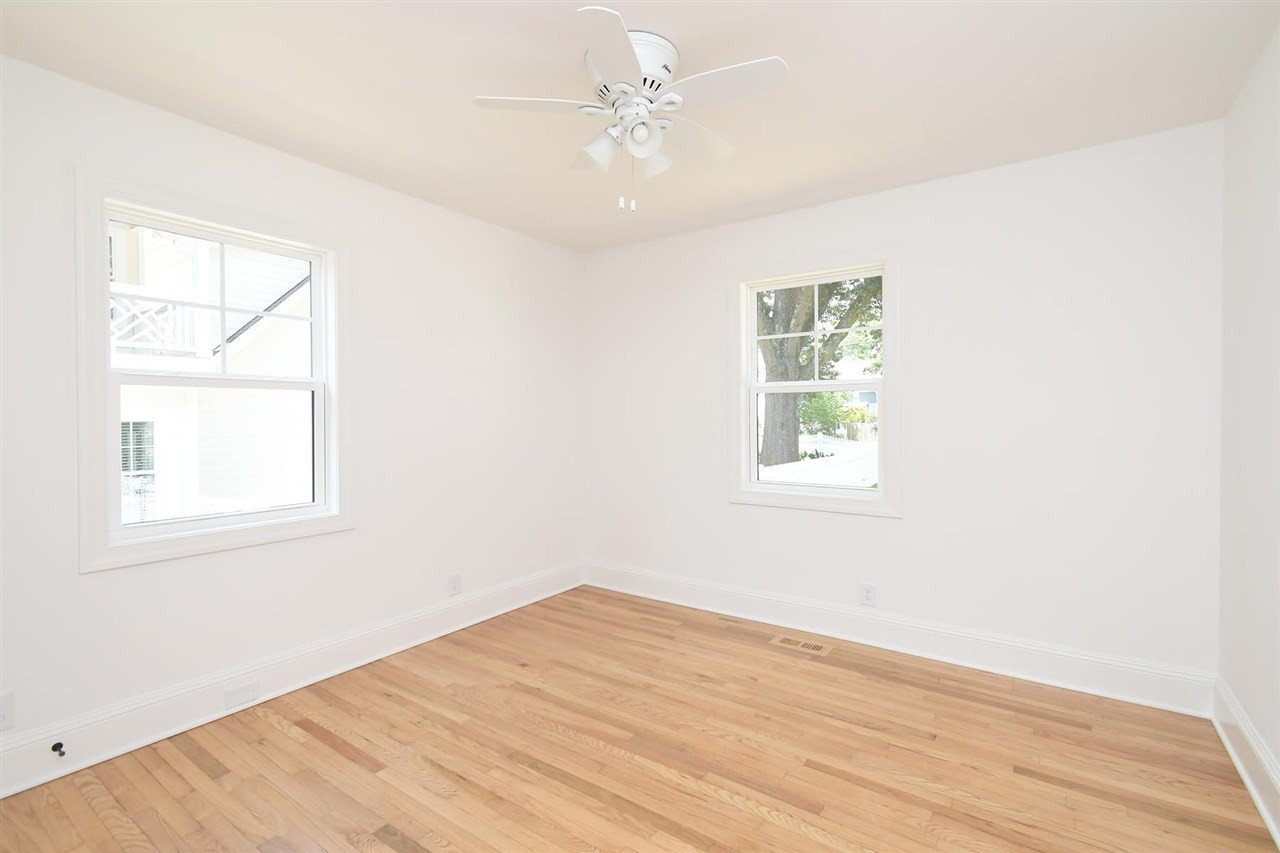2017 Pine Drive Raleigh, NC 27608 - Photo 21 of 25 an empty room with wooden floor chandelier fan and windows
