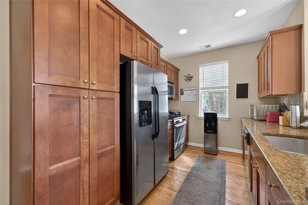 a kitchen with stainless steel appliances granite countertop a refrigerator a stove and a sink