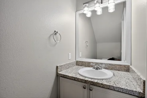 a bathroom with a granite countertop sink and a mirror