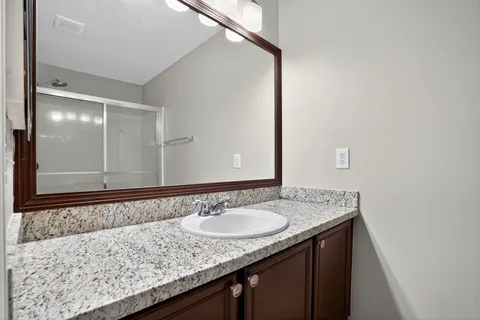 a bathroom with a granite countertop sink and a mirror