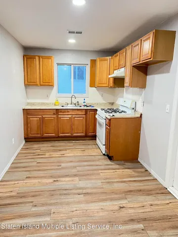 a large kitchen with granite countertop a stove top oven a sink dishwasher a dining table and chairs with wooden floor