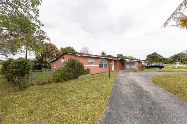 a view of a house with a yard and a large tree