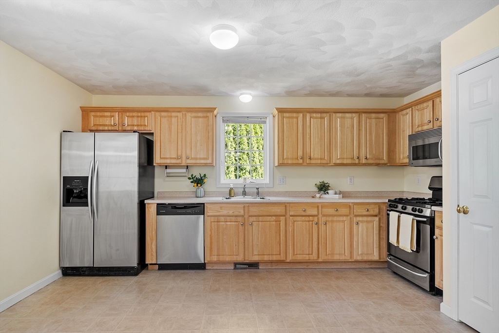 107 Charant Road Lowell, MA 01854 - Photo 9 of 30 a kitchen with stainless steel appliances granite countertop a refrigerator a stove a sink and white cabinets