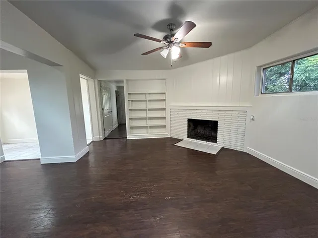 an empty room with wooden floor fireplace and window