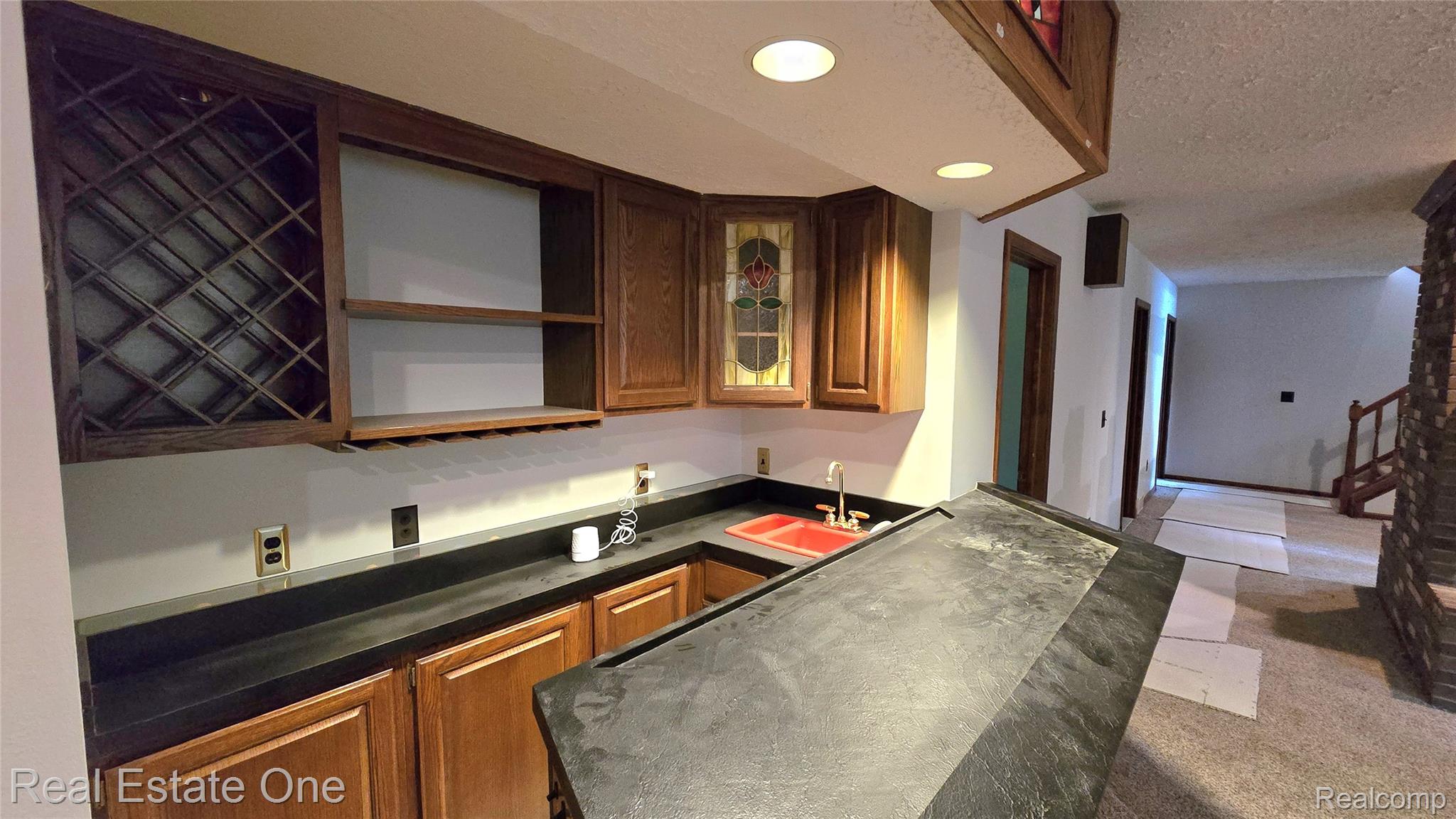 8950 Wise Road Commerce Township, MI 48382 - Photo 27 of 39 Wet bar featuring wood cabinetry, black countertops, a red sink, and recessed lighting