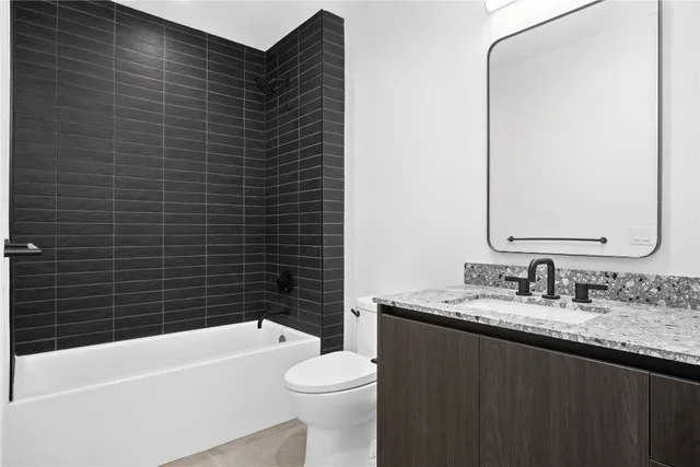 a bathroom with a granite countertop bathtub sink vanity mirror and toilet