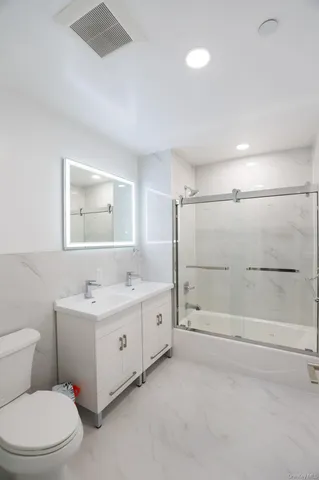 a kitchen with stainless steel appliances a stove top oven a sink a refrigerator and white cabinets