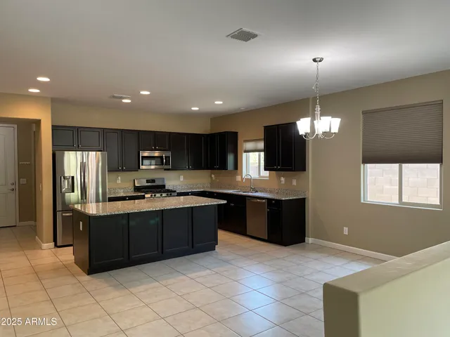 a large kitchen with stainless steel appliances kitchen island granite countertop a refrigerator and a stove top oven