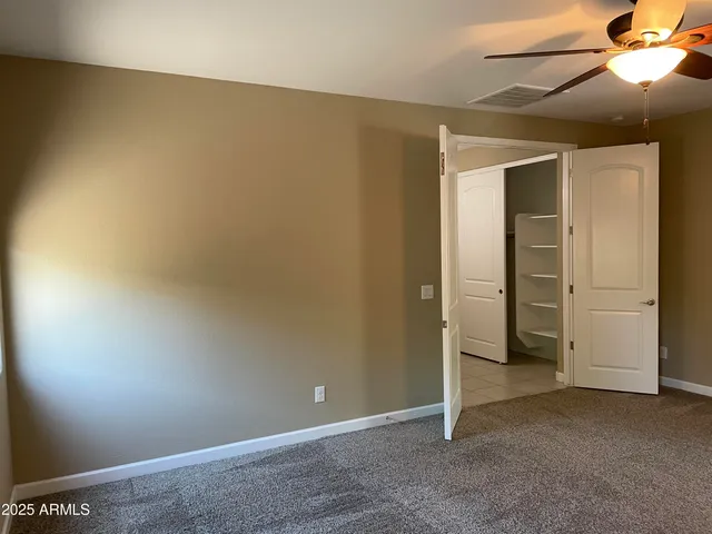 an empty room with closet and a chandelier fan