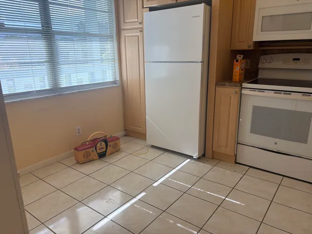 a view of a refrigerator in kitchen and an empty room