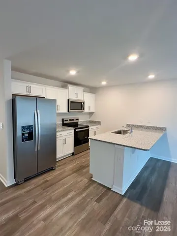 a kitchen with stainless steel appliances granite countertop a refrigerator a stove and a sink