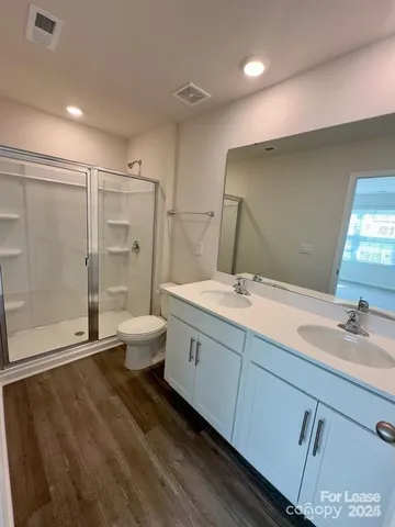 a bathroom with a double vanity sink toilet mirror and shower