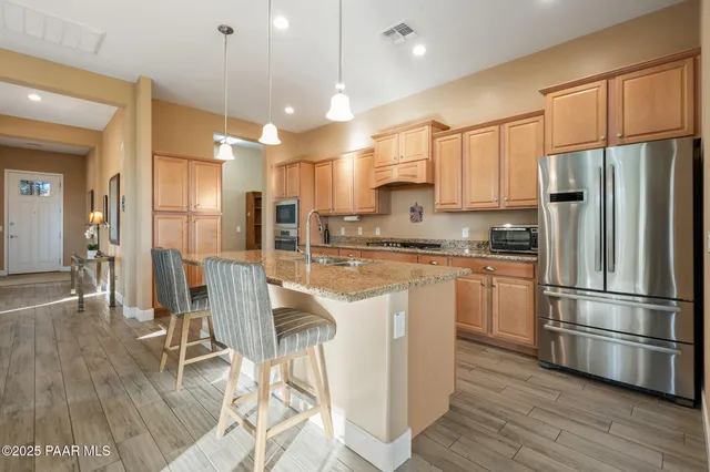 a kitchen with stainless steel appliances granite countertop a refrigerator a stove a sink dishwasher and a refrigerator with wooden floor