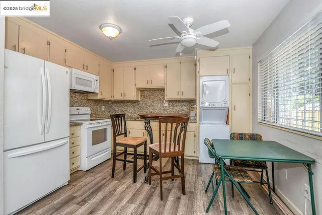 a kitchen with stainless steel appliances granite countertop a stove a refrigerator a dining table and chairs with wooden floor