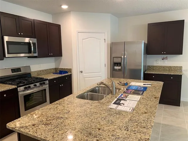 a kitchen with stainless steel appliances granite countertop a sink stove and refrigerator