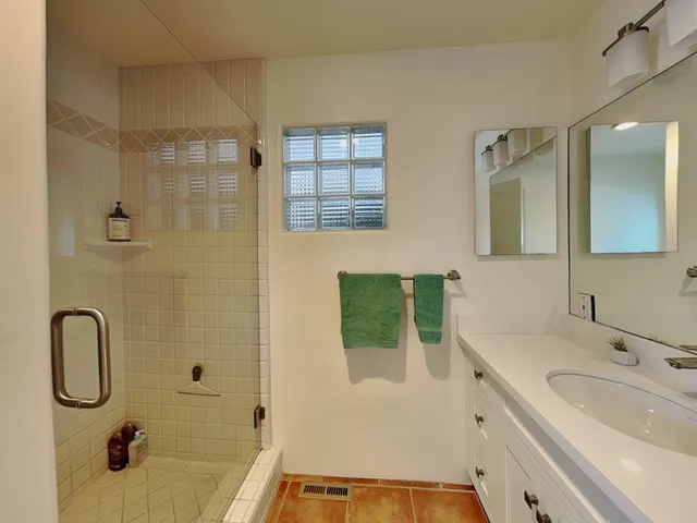 a bathroom with a granite countertop sink a mirror a vanity and shower