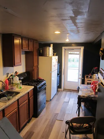a kitchen with a stove a refrigerator and wooden floor