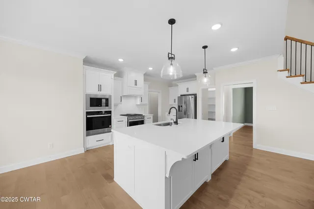 a large kitchen with stainless steel appliances kitchen island a stove a refrigerator a oven and a sink with large countertops