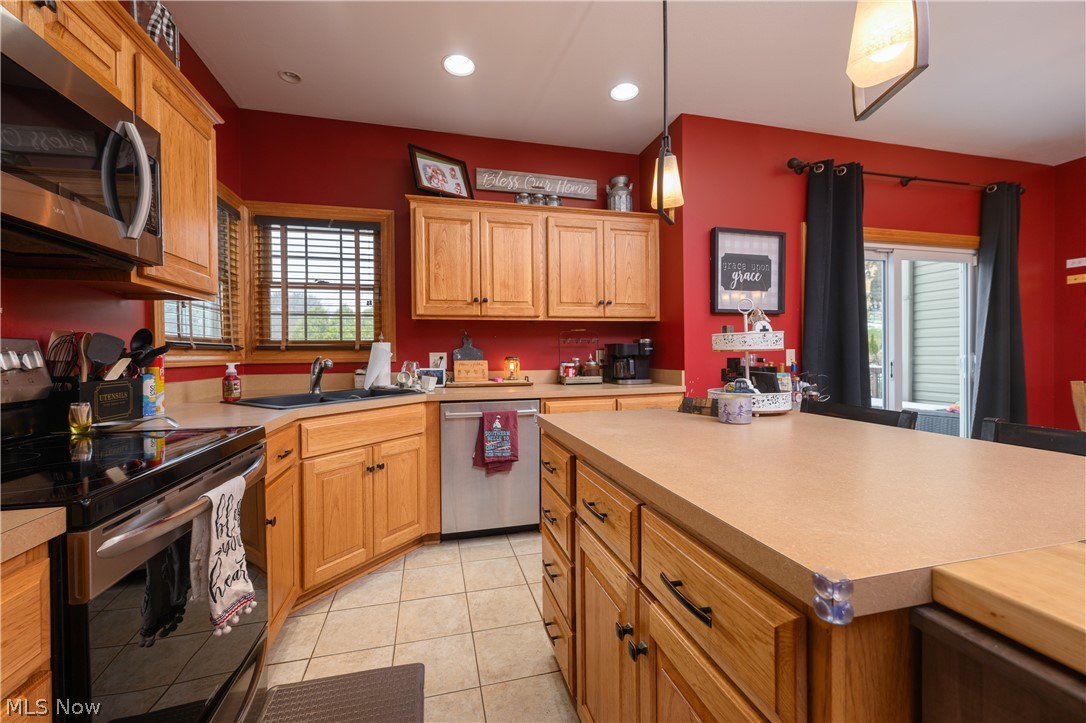 806 Forrest Ridge Drive Dover, OH 44622 - Photo 17 of 36 Kitchen with stainless steel appliances, light countertops, hanging light fixtures, and light tile patterned floors
