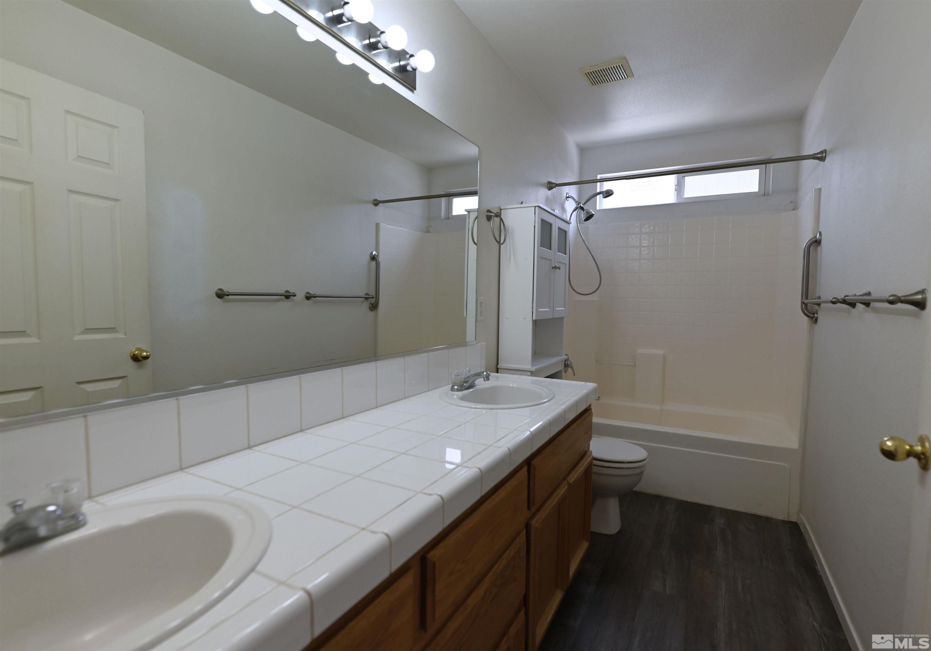 2129 Fort Bridger Road Fernley, NV 89408 - Photo 10 of 21 a bathroom with a granite countertop sink a toilet a mirror and shower