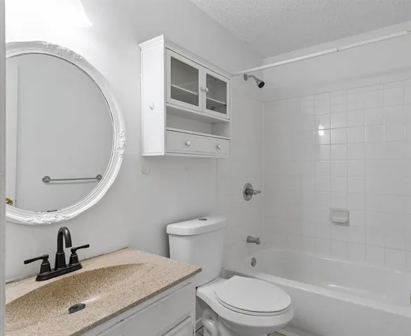 a bathroom with a granite countertop toilet a sink and a mirror