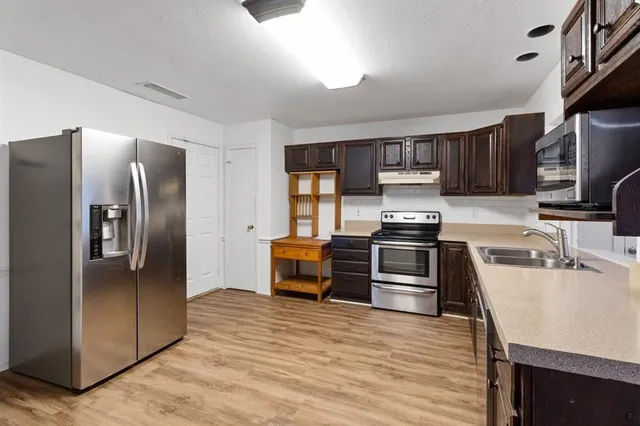 a kitchen with granite countertop a refrigerator and a stove top oven