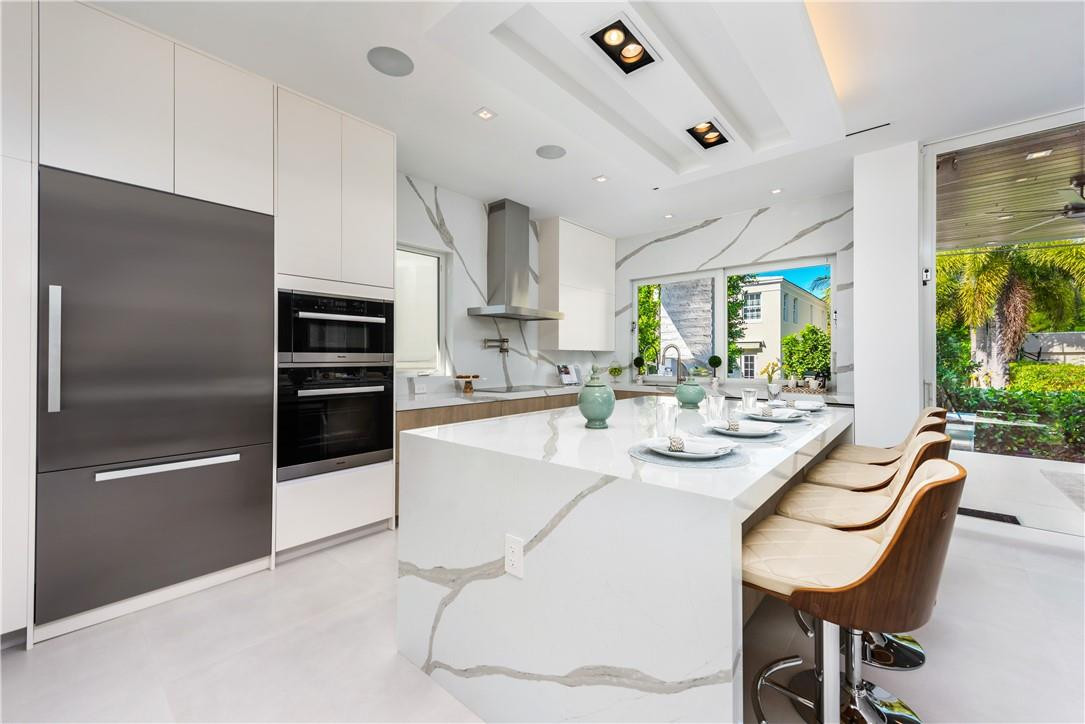 4610 Alton Road Miami Beach, FL 33140 - Photo 9 of 60 a kitchen with stainless steel appliances kitchen island granite countertop a refrigerator a stove a sink a dining table and chairs with wooden floor