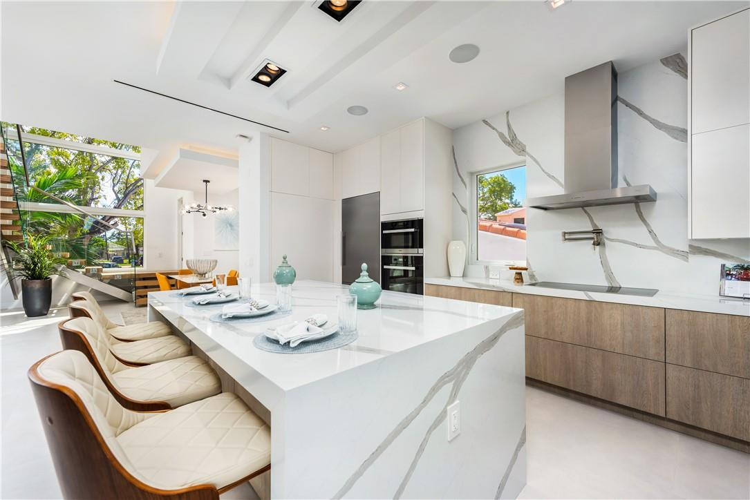4610 Alton Road Miami Beach, FL 33140 - Photo 10 of 60 a kitchen with stainless steel appliances kitchen island granite countertop a sink a stove a table and chairs