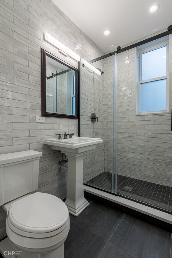 2318 West Thomas Street, Unit 3R Chicago, IL 60622 - Photo 10 of 12 a bathroom with a toilet a sink a mirror and shower