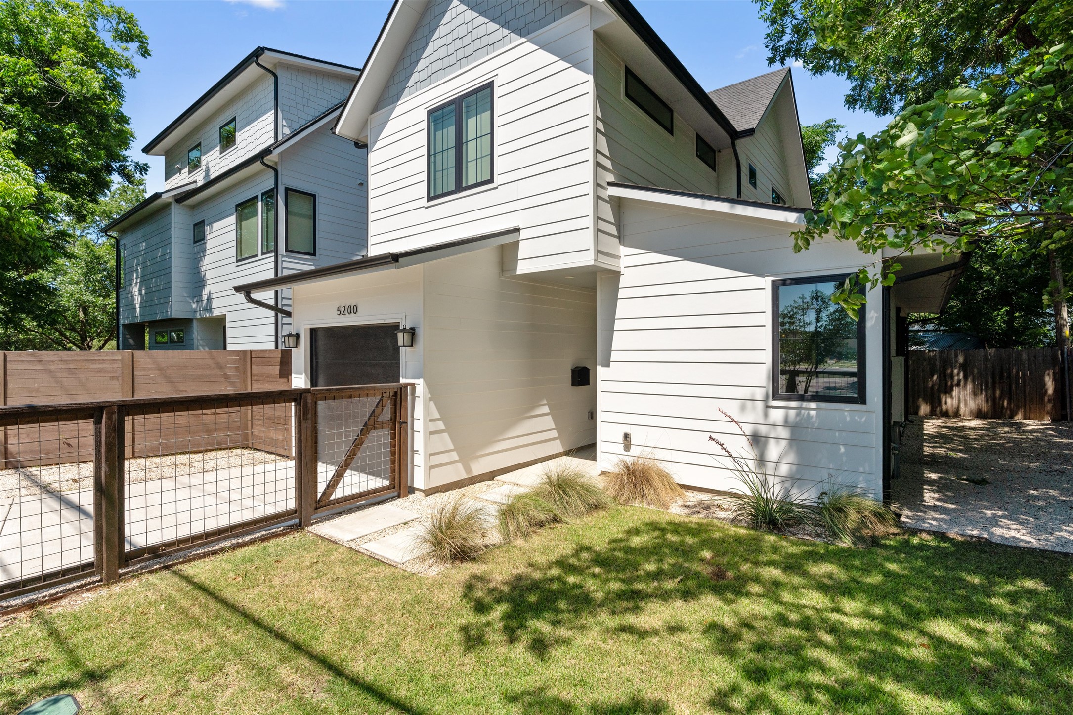 5200 Grover Avenue Austin, TX 78756 - Photo 4 of 32 Modern multi-story exterior with white horizontal siding and dark trim windows. Fully fenced front yard with a side entrance gate off the driveway. Beautifully landscaped with automatic in ground sprinkler system.