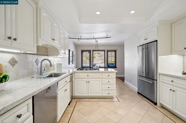 a kitchen with stainless steel appliances granite countertop a stove a sink dishwasher and a refrigerator with white cabinets