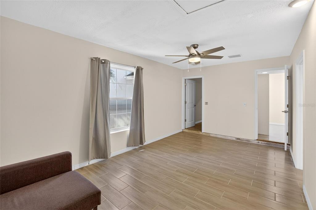 15047 Woodbury Road Brooksville, FL 34604 - Photo 14 of 98 a view of a livingroom with a ceiling fan a kitchen space with wooden floor and a ceiling fan