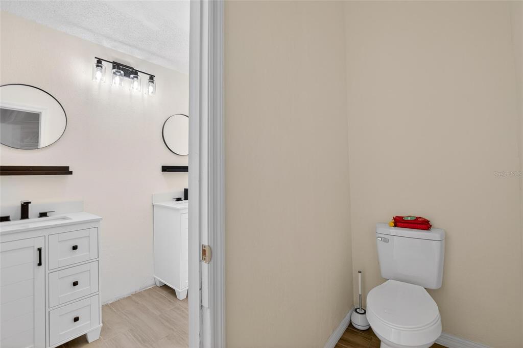 15047 Woodbury Road Brooksville, FL 34604 - Photo 19 of 98 a bathroom with a toilet sink vanity and mirror