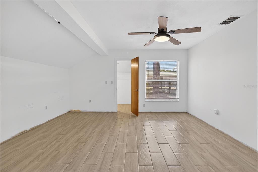 15047 Woodbury Road Brooksville, FL 34604 - Photo 31 of 98 a view of an empty room with wooden floor and a ceiling fan