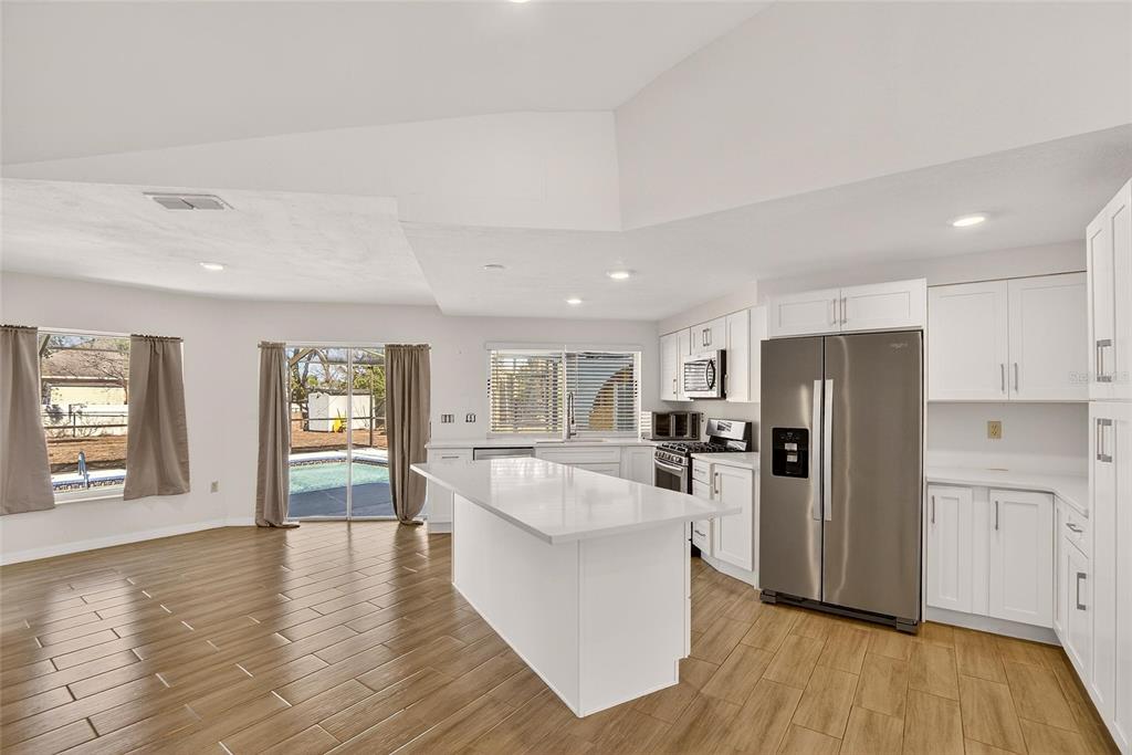 15047 Woodbury Road Brooksville, FL 34604 - Photo 36 of 98 a large kitchen with a center island wooden floor and stainless steel appliances