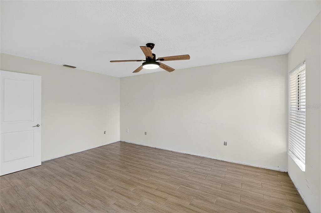 15047 Woodbury Road Brooksville, FL 34604 - Photo 45 of 98 a view of a room with wooden floor and a ceiling fan