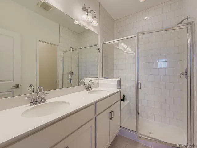a bathroom with a double vanity sink mirror and shower