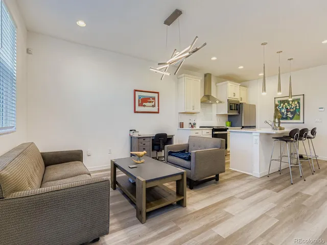 a living room with furniture kitchen view and a wooden floor