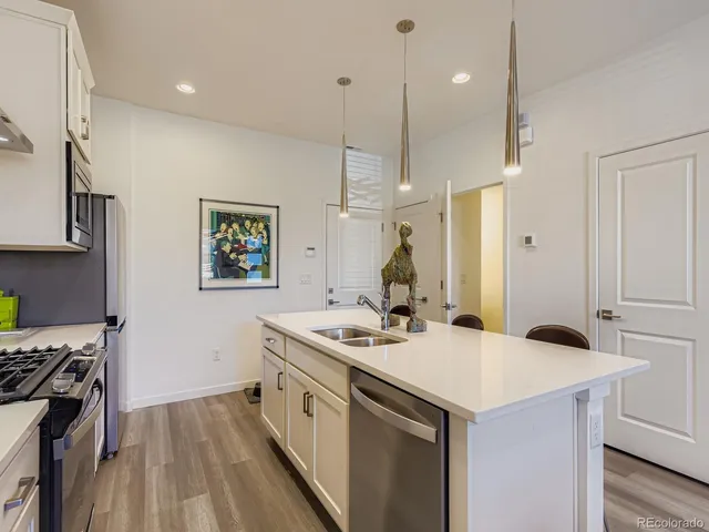 a kitchen that has a sink a stove and a wooden floor