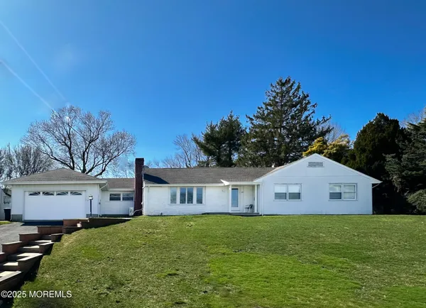a front view of house with yard and trees in the background