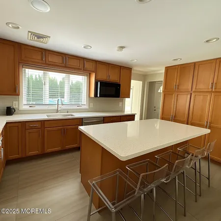 a kitchen with stainless steel appliances kitchen island granite countertop a sink a stove a dining table and chairs