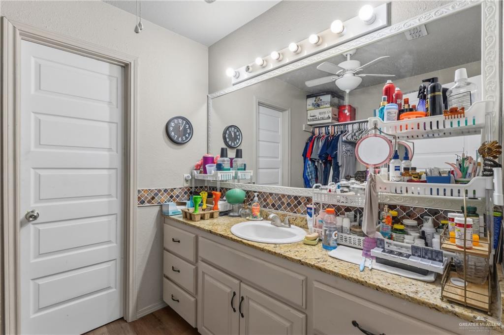 29246 26th Road San Benito, TX 78586 - Photo 13 of 23 Vanity featuring a built-in sink, granite countertop, and mosaic tile backsplash