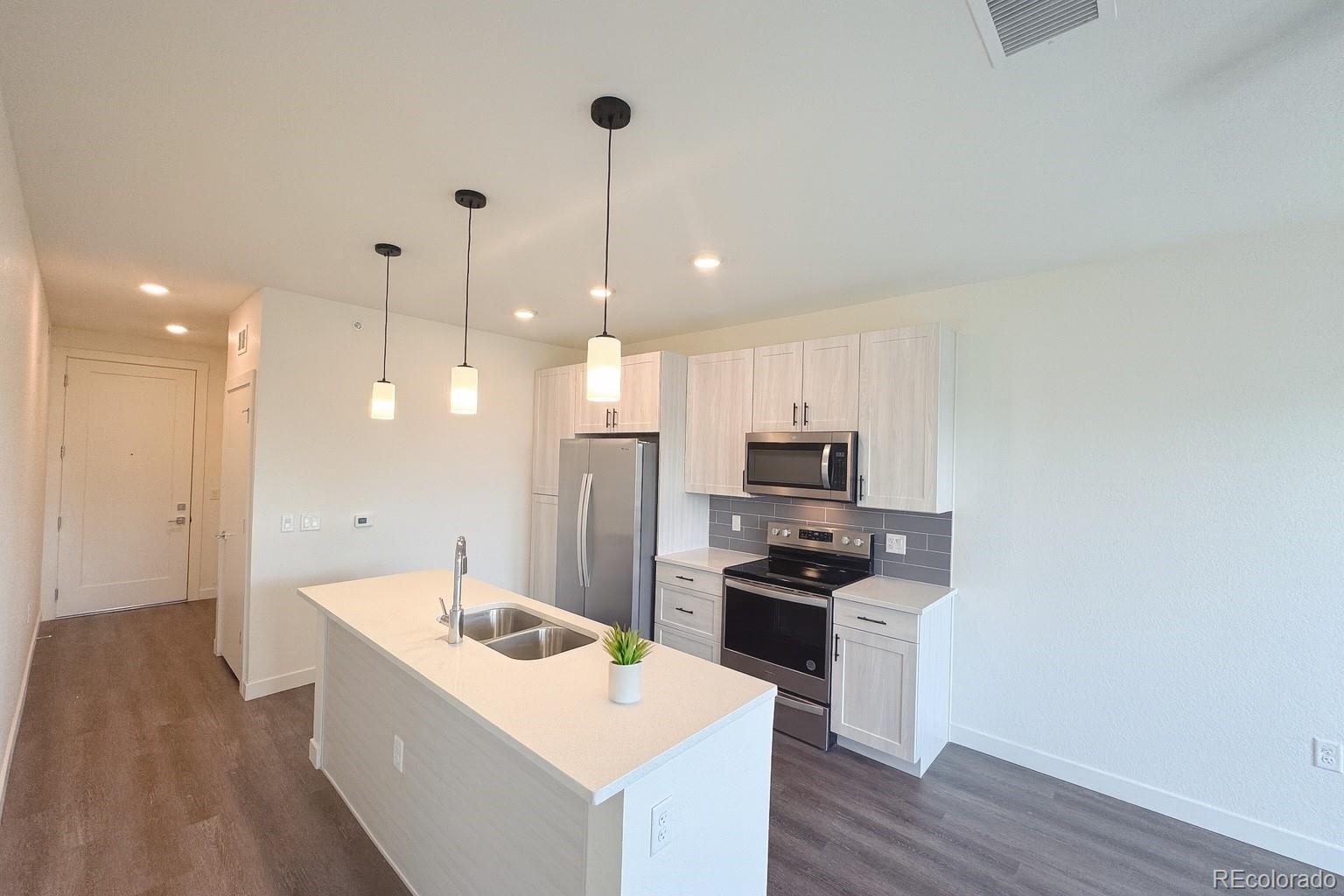 4900 West 29th Avenue, Unit 310 Denver, CO 80212 - Photo 1 of 13 a kitchen with kitchen island a sink stainless steel appliances and wooden floor